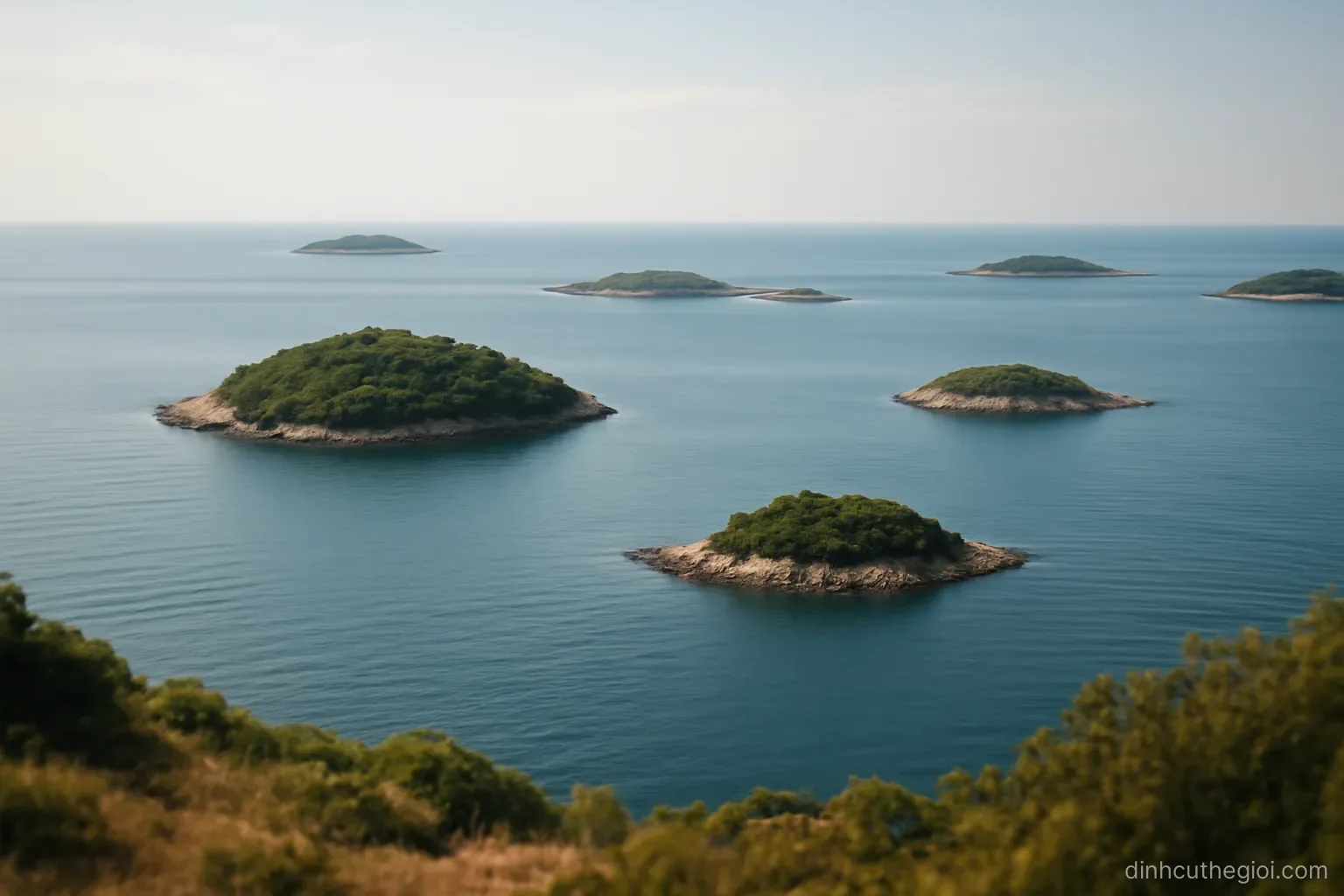 several small islands of different sizes scattered across calm sea seen from a high vantage point