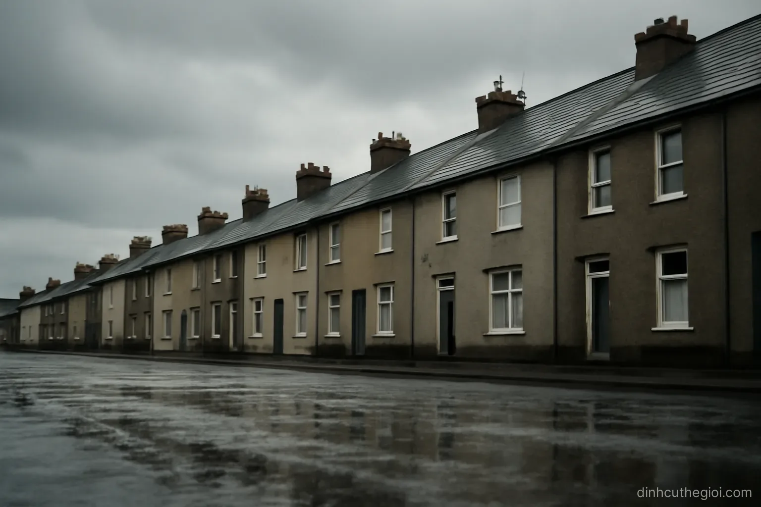 a grey overcast sky above a row of rooftops with wet pavement reflecting a dull light below